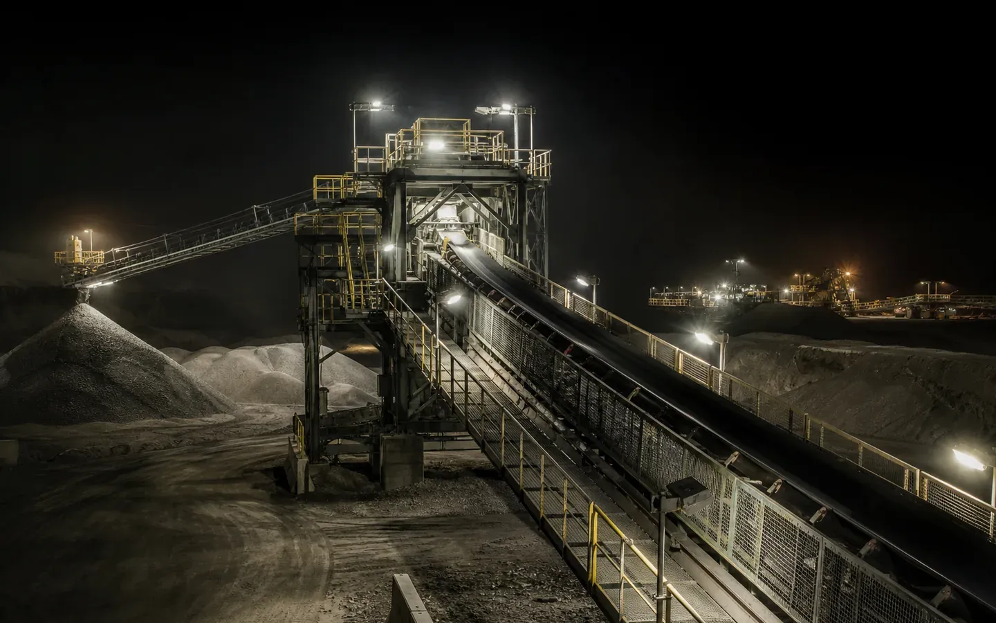 Rugged LED luminaires illuminating a dusty mining conveyor and stockyard at night