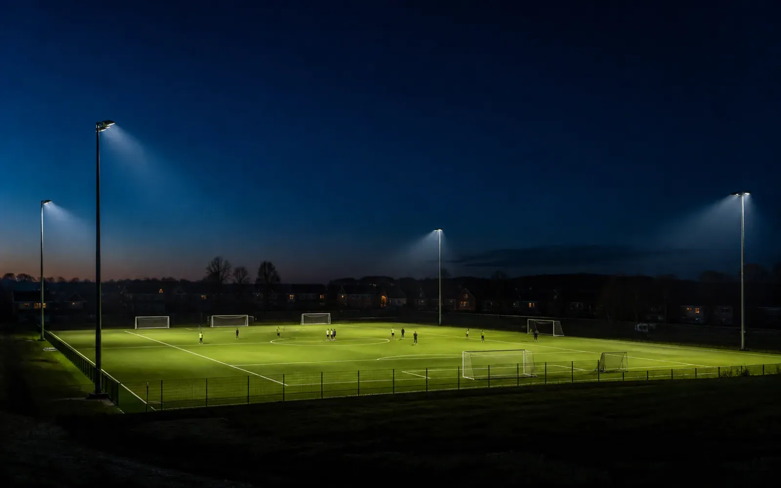 Shielded outdoor sports floodlights aimed onto a field with dark surroundings